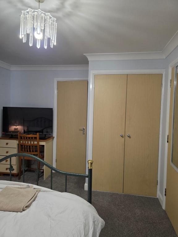 a bedroom with a bed and a chandelier at Near recreation park in Colchester