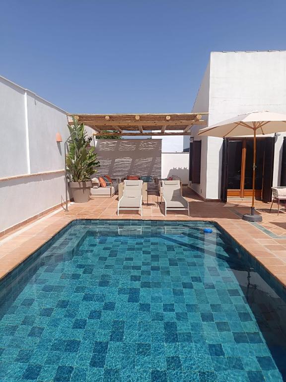 a swimming pool with chairs and an umbrella at Villa Mara Valle Golf Resort in Murcia