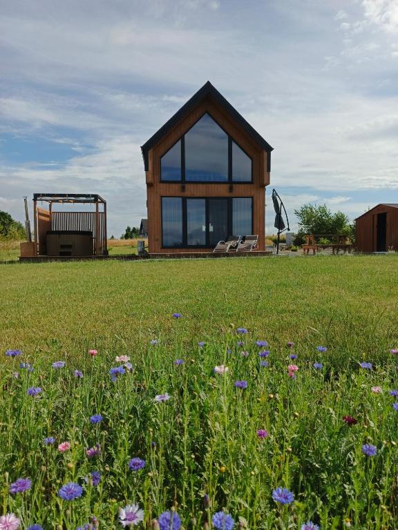 a small wooden house in a field with flowers at Zielone Wzgórze komfortowy klimatyzowany domek z balią z aeromasażem in Kłodzko
