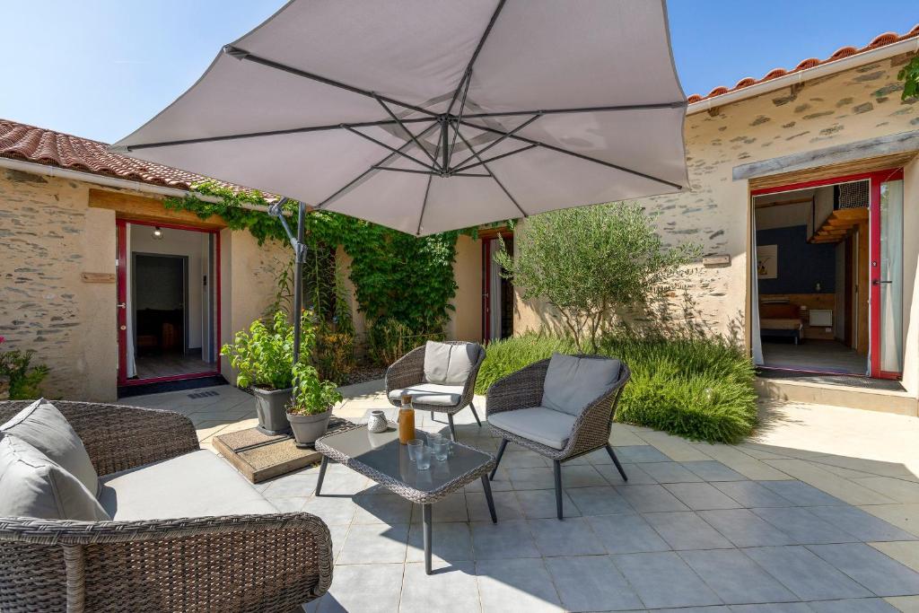 a patio with a table and chairs and an umbrella at Le Cocon Vendéen Chambres D'hôtes in Saint-André-Goule-dʼOie