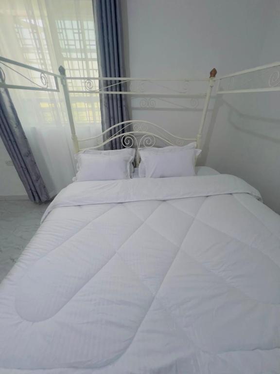 a white bed with white sheets and pillows in a bedroom at Rv delight suite in Nairobi
