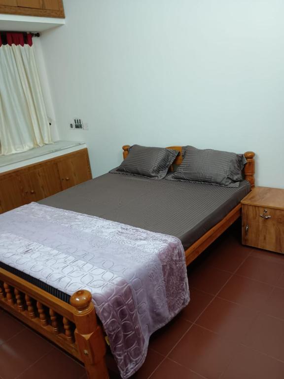 a bedroom with a wooden bed with a gray blanket at Aanchal Nest in Mangalore