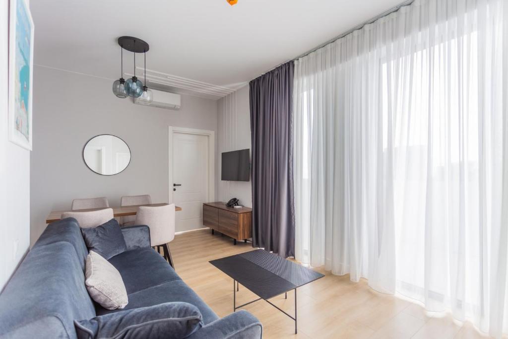 a living room with a blue couch and a table at Nova Concierge Aparthotel in Batumi