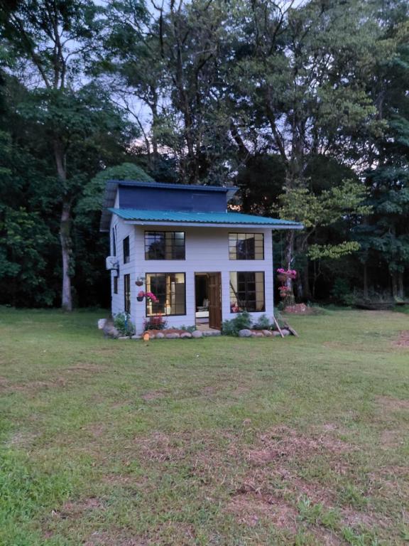 a white house with a blue roof in a yard at Bosque Alto Lodge in Platanal