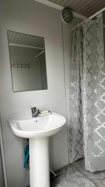 ein Badezimmer mit einem weißen Waschbecken und einem Spiegel in der Unterkunft KölToo in Barskoon