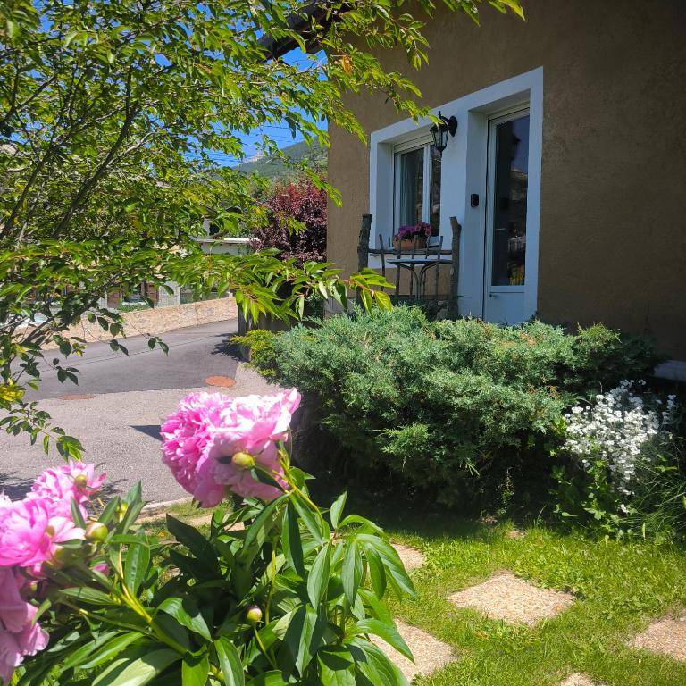 a garden with pink flowers in front of a house at Chambre Studette indépendante in Briançon