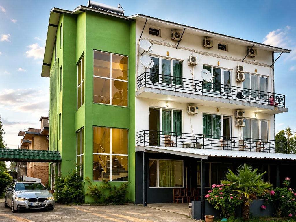 a green and white building with a car parked in front at Mziuri Guest House in Ureki