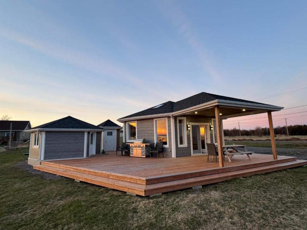 a modular home with a deck in a field at Waterfront & breathtaking view - Chalet du Phare in Bonaventure