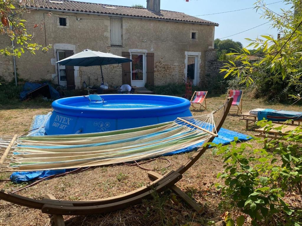 a deck chair with a blue tub in front of a house at La Grange des zarts in Champagné-le-Sec