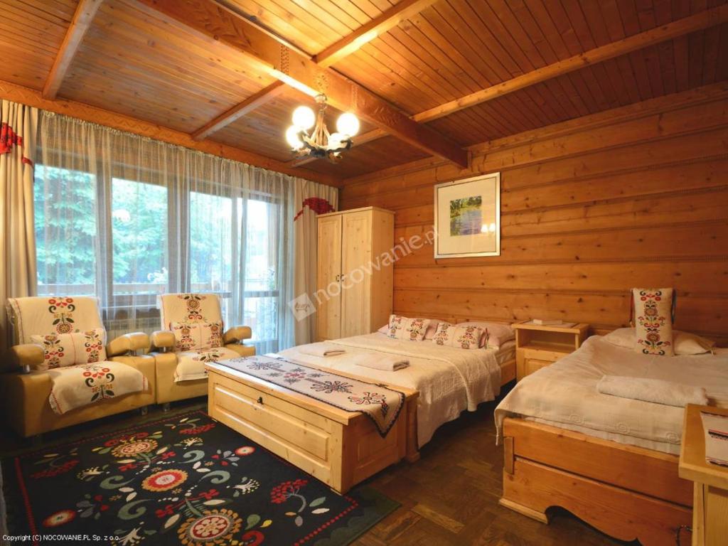 um quarto com 2 camas, uma cadeira e uma janela em Zakońpiańska Chata - Domek Góralski Na Kamieńcu em Zakopane