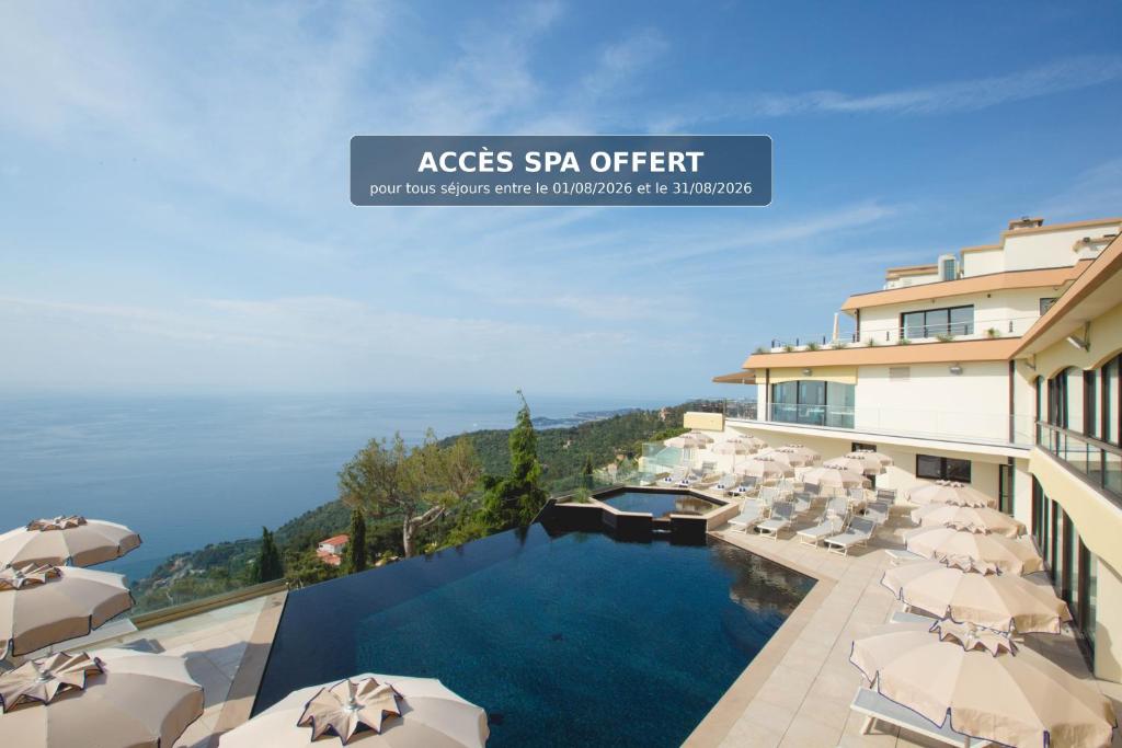 a hotel with a swimming pool with umbrellas at Les Terrasses d'Eze - Hôtel & Spa in Éze