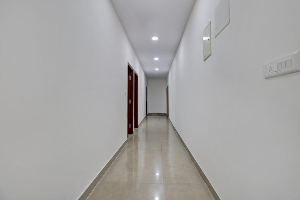 a hallway of a building with white walls and floors at Hotel O Maruthi Paradise Netaji Udyanavana Park in Bangalore