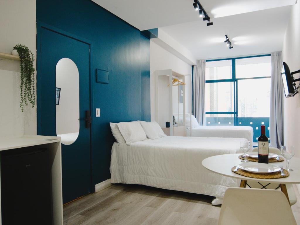 a blue and white bedroom with a bed and a table at Apê Metrô Paraíso in São Paulo