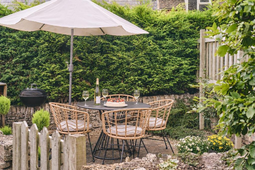 a table and chairs with an umbrella in a garden at Squirrel Barn in Moreton in Marsh
