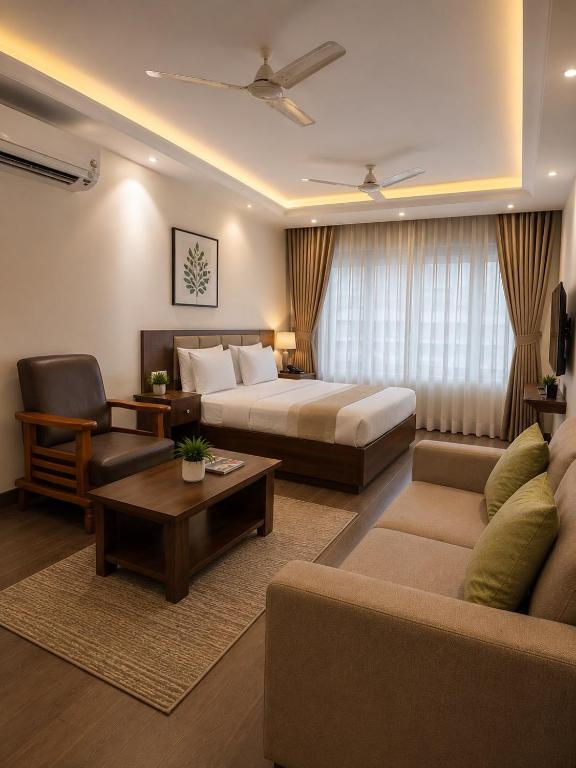 ein Hotelzimmer mit einem Bett, einer Couch und einem Tisch in der Unterkunft Red Queen in Raigarh