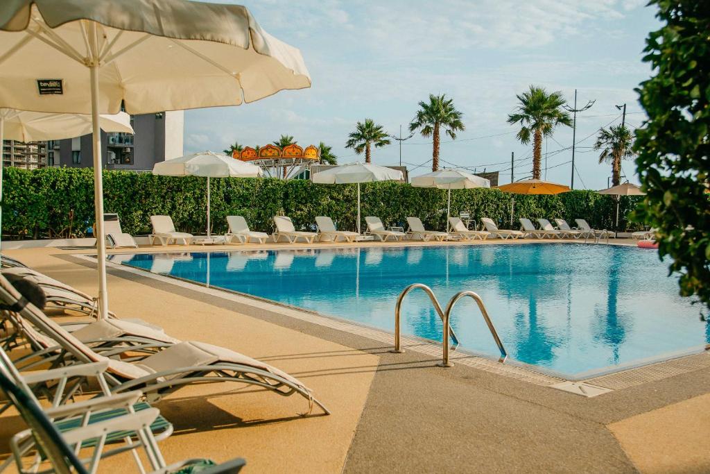 a swimming pool with lounge chairs and an umbrella at Era Palace Gonio in Kvariati