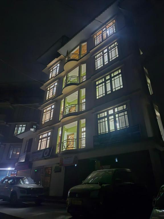 a tall building with lit up windows at night at Tilanjali Stay in Soreng