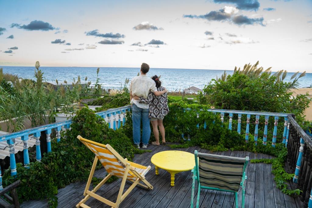 a man and woman standing on a deck looking at the beach at Cap carav'ânes in Banī ‘Aţāʼ