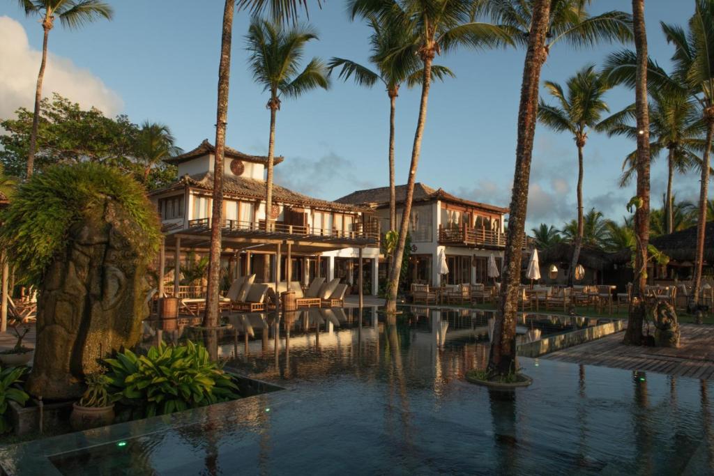 a resort with a swimming pool and palm trees at Pousada Vila do Mar in Caraíva