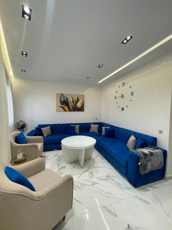 a living room with a blue couch and chairs at Appartement direct aan zee in Azla-Tetouan in Azla