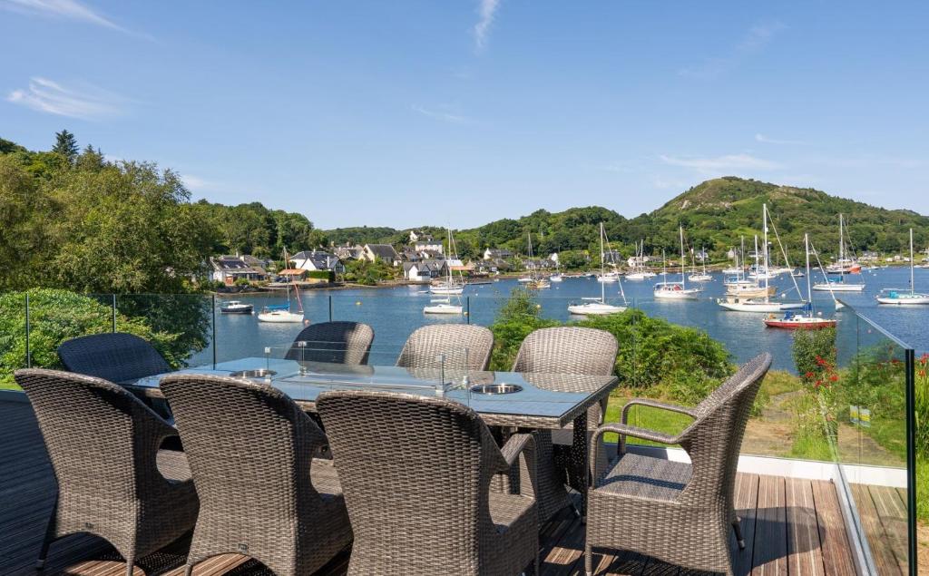a table and chairs on a balcony overlooking a marina at Otterpoint Waterfront & Pool Retreat in Tayvallich