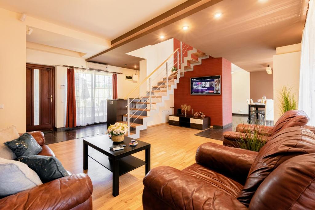 a living room with leather couches and a staircase at CROSS SQUARE HOUSE - Spacious 2 Level Home, 2BR, 3Baths, Terrace - by RealTrust in Timişoara