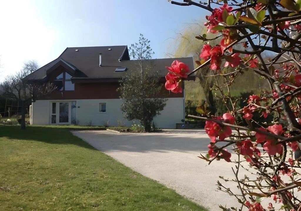 a house with red flowers in front of a driveway at Chalet La Bachole - Chambre d'hôtes in Charancieu
