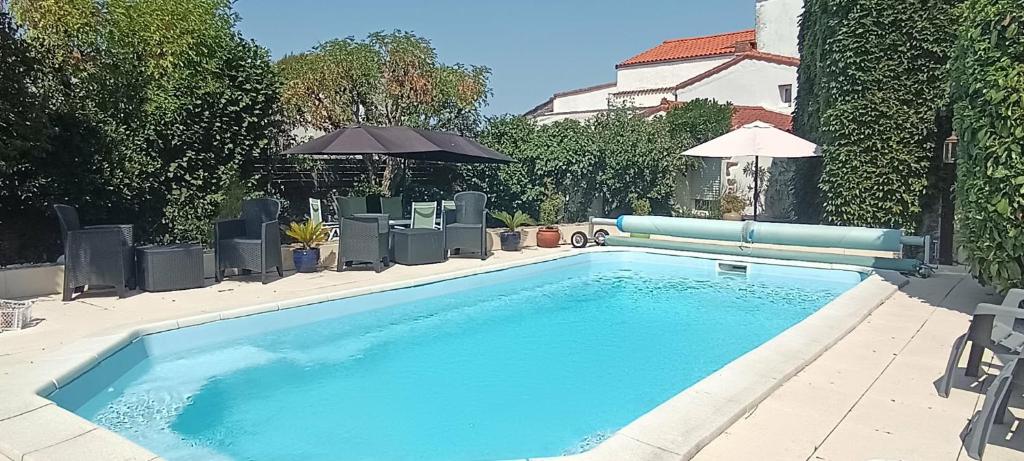 a large blue swimming pool with an umbrella and chairs at La Fleur de Lys in Moulins