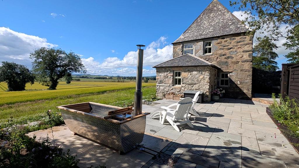 a stone house with a tub and a white chair at The Lodges @ Barra Castle in Inverurie
