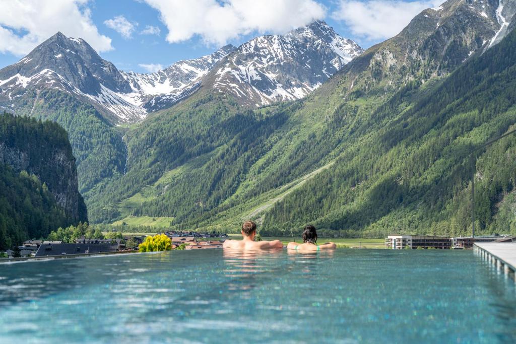 a man and woman sitting in the water in the mountains at Hotel Stern in Längenfeld