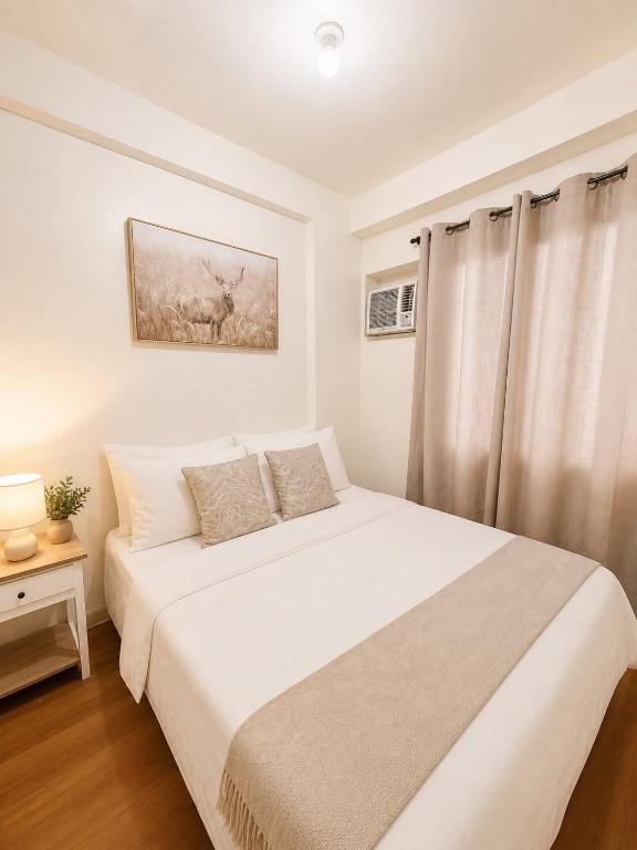a white bedroom with a bed and a window at Camella Northpoint condominium in Davao City