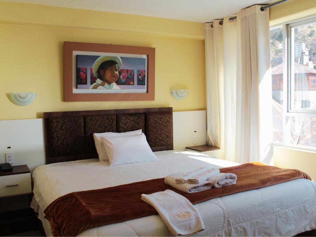 a bedroom with a bed with two towels on it at Kaaro Hotel Suite in Puno