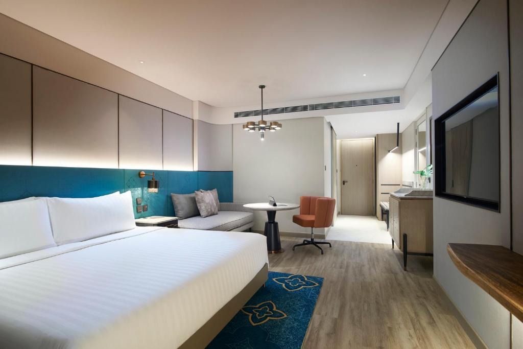 A spacious contemporary king room with a sofa, work chair, television, and kitchenette-style counter.