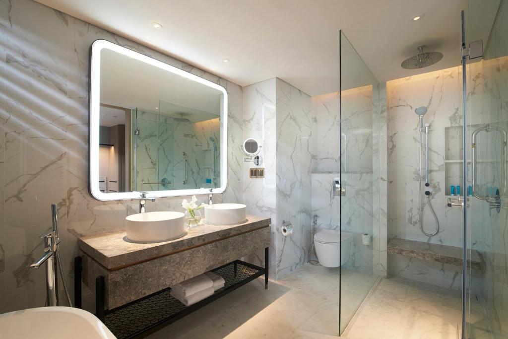 A marble bathroom with twin vessel sinks and a glass-enclosed rain shower.