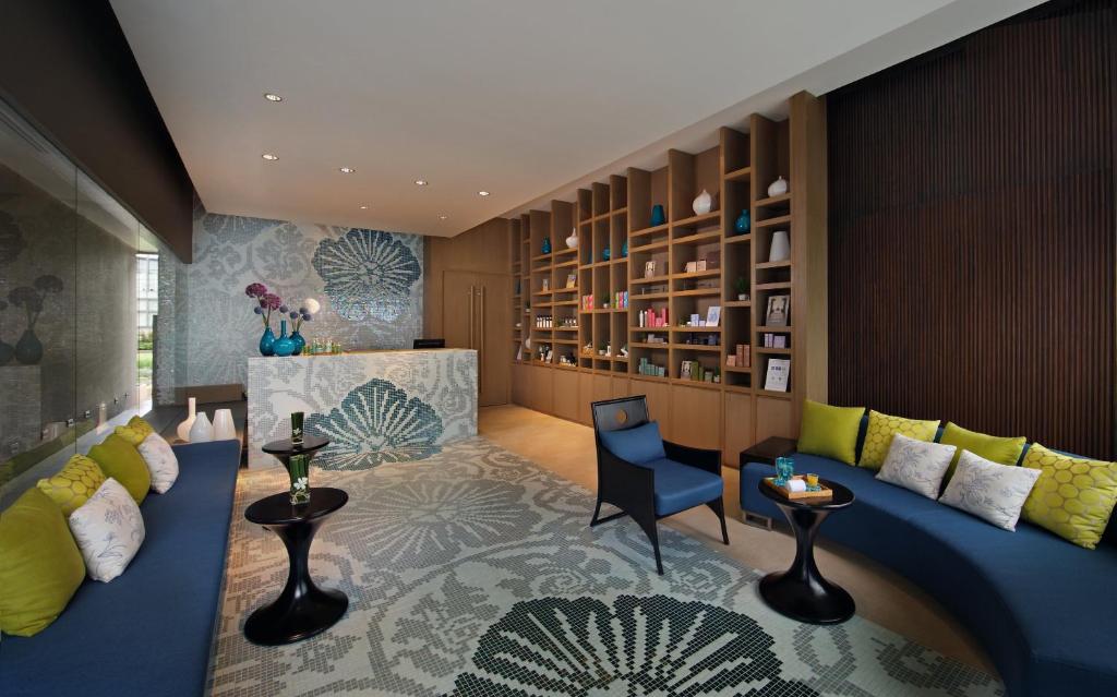 A colorful lounge with curved blue sofas, armchairs, and decorative shelving.