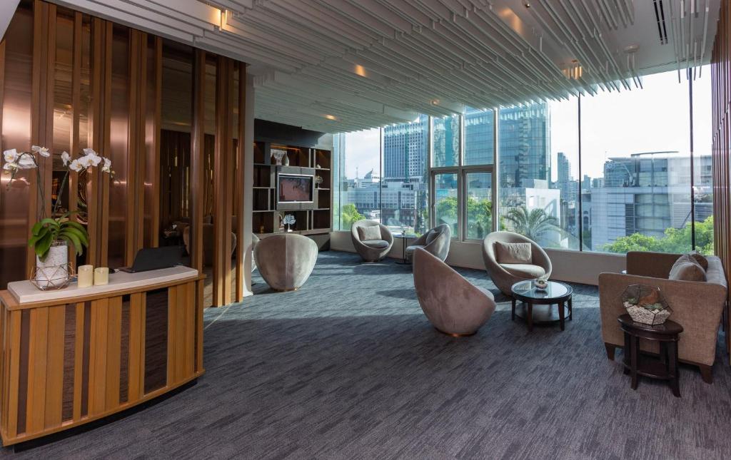 A quiet lounge-workspace overlooks Bangkok through a wall of large windows.