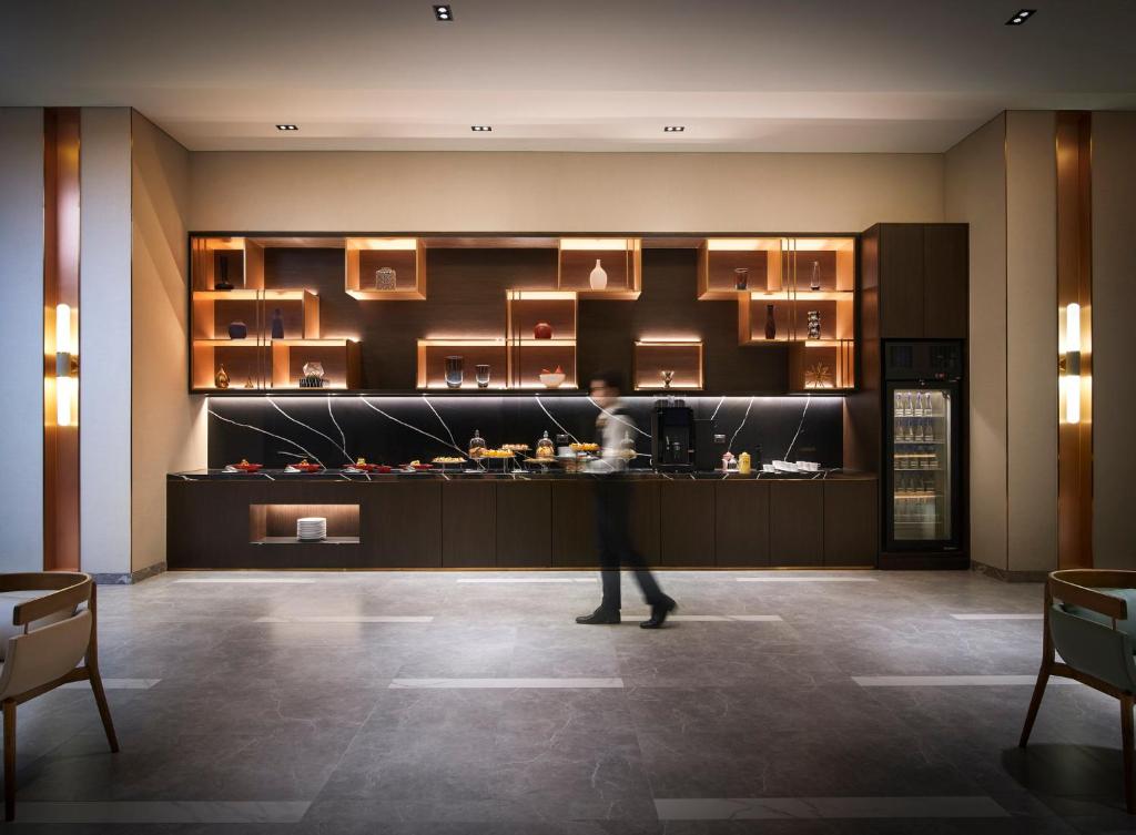 A staffed refreshment counter forms the focal point of a modern lobby wall.
