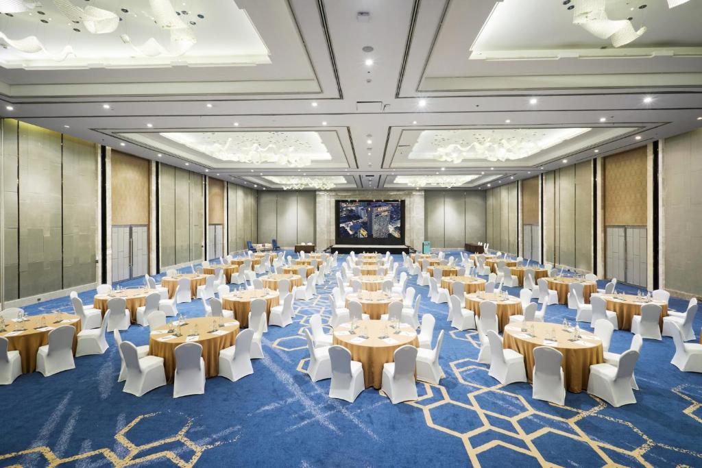 A large banquet hall arranged with round tables, white-covered chairs and a presentation screen.