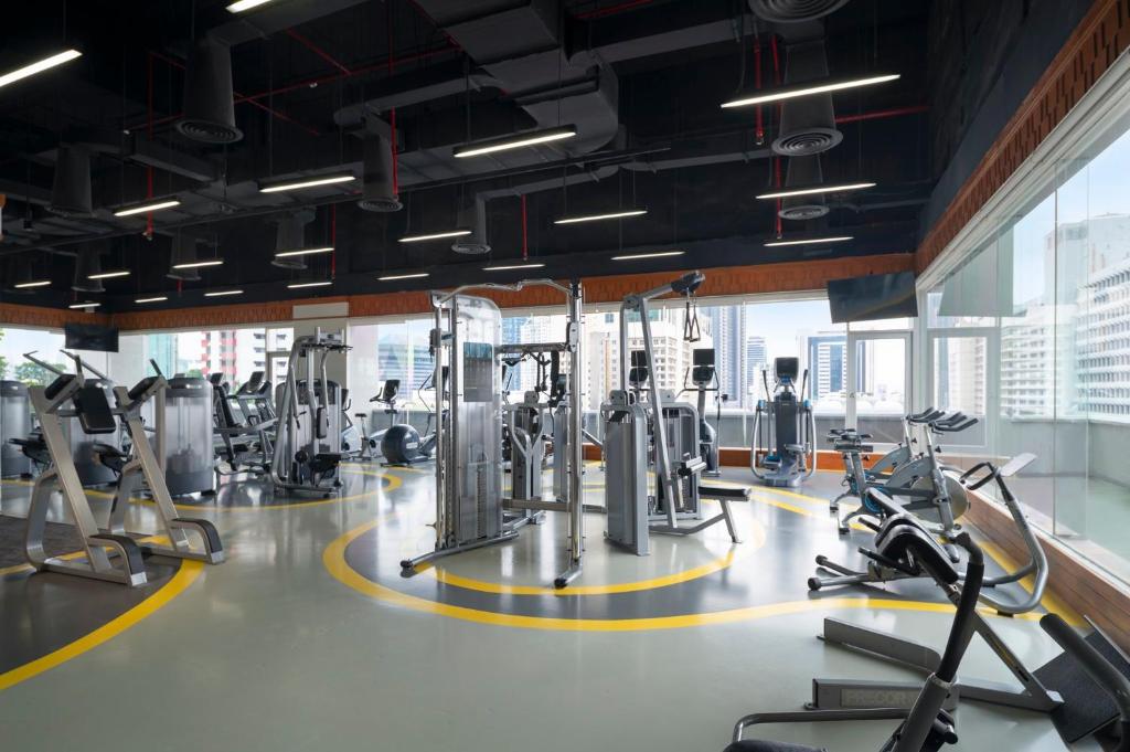 A bright fitness room with cardio machines, strength equipment, and city views.