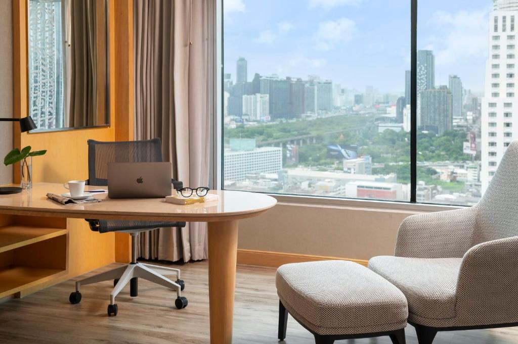 A compact work desk beside a full-height window overlooking Bangkok.