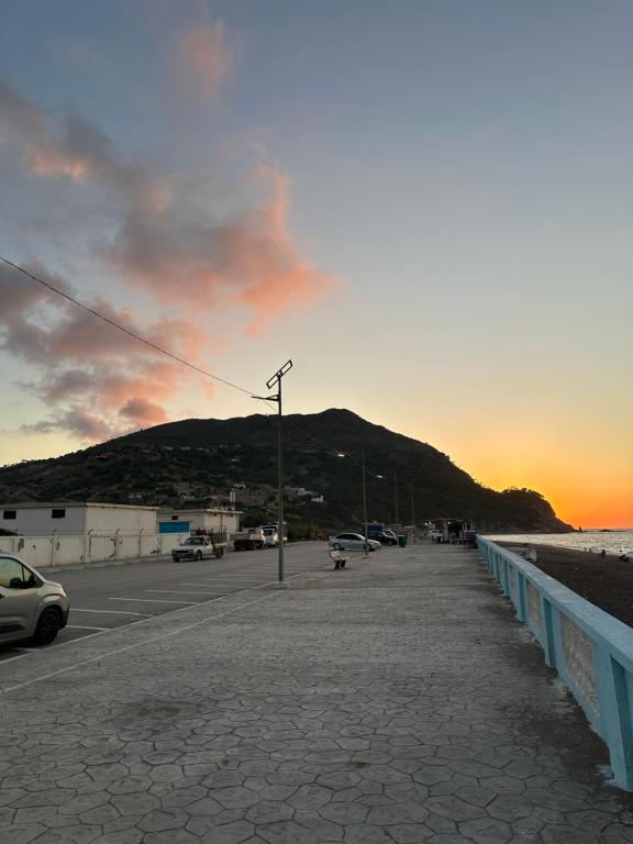 a sidewalk next to a beach with a sunset at el sahel residence in Beni Haoua