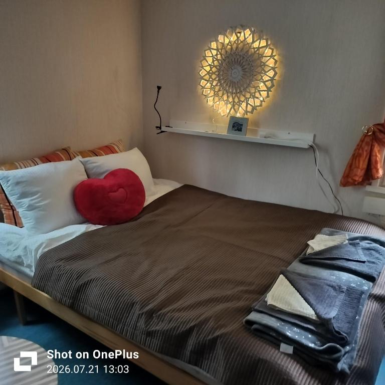 a red heart pillow on a bed with a mirror on the wall at Retro House in Savonlinna
