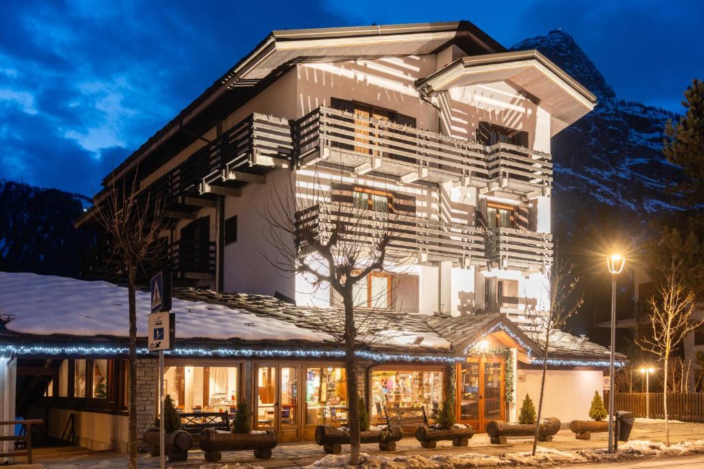 a large white building with snow on it at night at Hotel Les Jumeaux Courmayeur in Courmayeur
