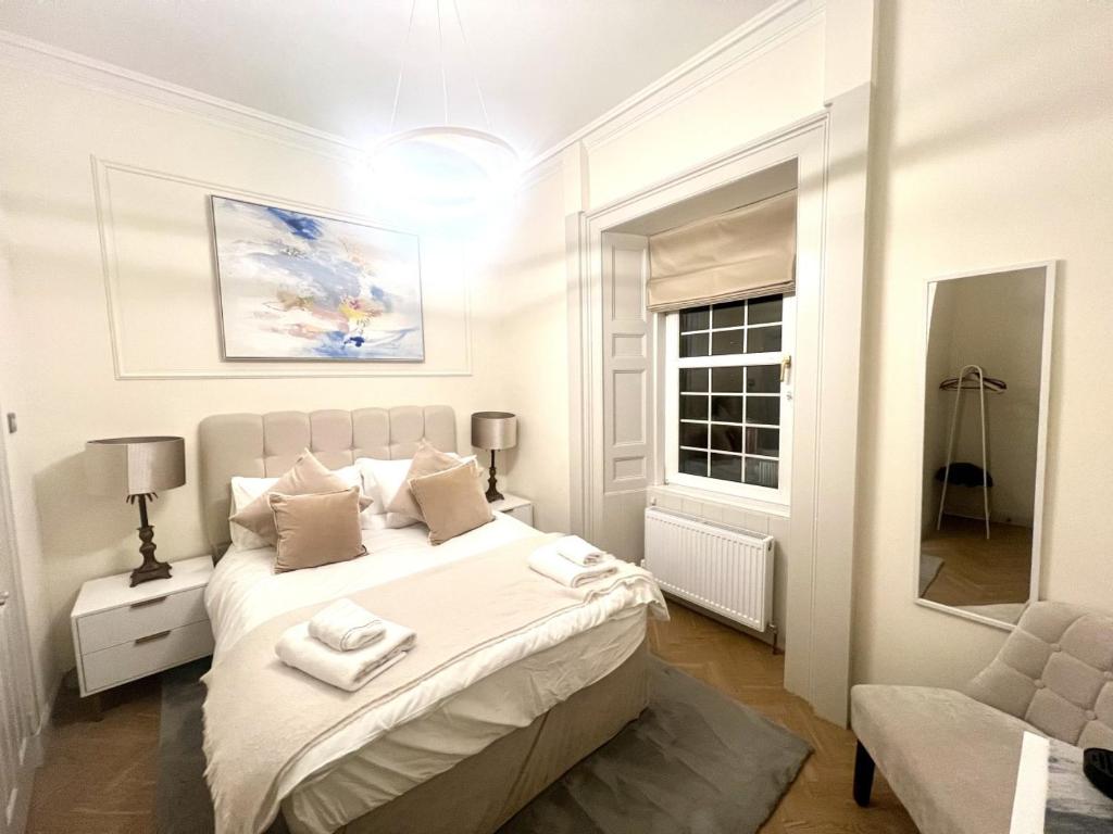 a white bedroom with a bed and a mirror at 'Maisie' in ApartNest Auchterarder in Auchterarder