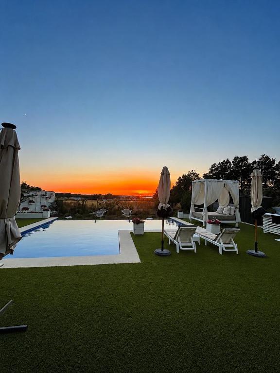 a pool with chairs and umbrellas and a sunset at Puesta de Sol Doñana Adults Only in Sanlúcar de Barrameda