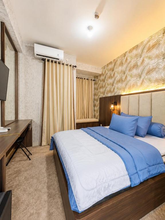 a bedroom with a large bed with blue pillows at Transpark Cibubur by 21room in Kalimanggis