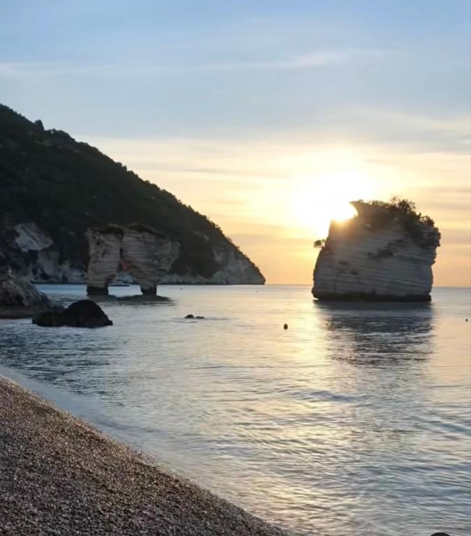 a sunset on the beach with two large rocks in the water at Spina home in Vieste