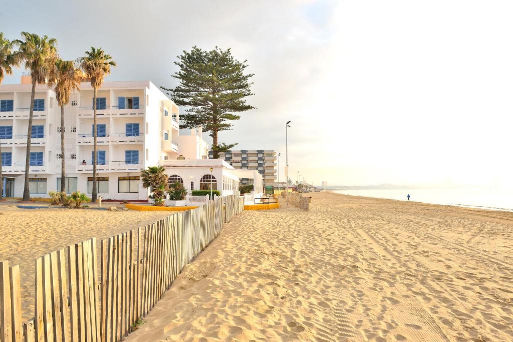 una playa con una valla y un edificio en El Bahía Algeciras, en Algeciras