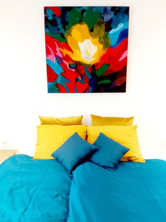 a bed with blue sheets and a painting above it at Luxury Suites Oosterwold in Almere