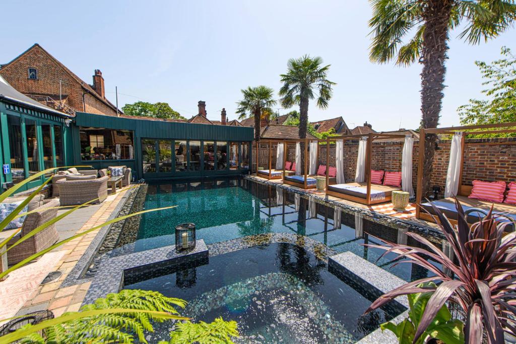 a swimming pool with chairs and a building at Crazy Bear Beaconsfield in Beaconsfield